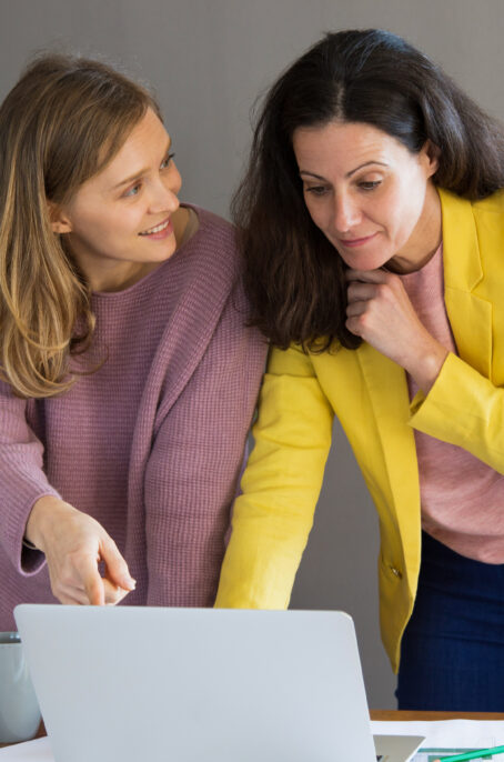 Two women standing at desk with laptop
