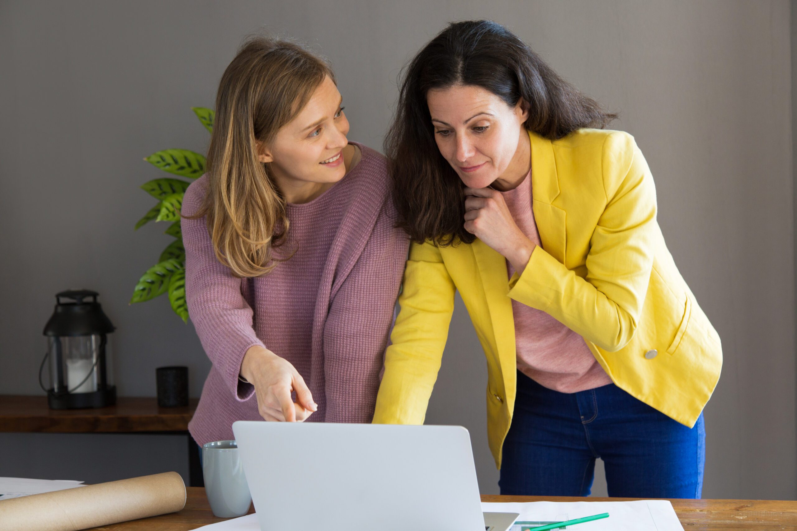 Two women standing at desk with laptop